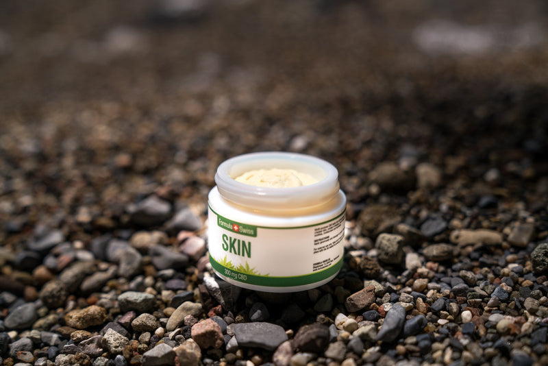 Atvērta Formula Swiss CBD Skin balzama burciņa, 300 mg CBD, oļu pludmalē